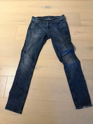 Slimfit dondup jeans - Säljer ett par mörkblåa slimfit jeans från Dondup, tillverkade i Italien. Jeansen har klassisk femficksdesign, smal passform och snygga slitningar på låren och knäna. Materialet är mjukt jeans-tyg och färgen är mörkblå med ljusare tvättade partier. W-28 L30
