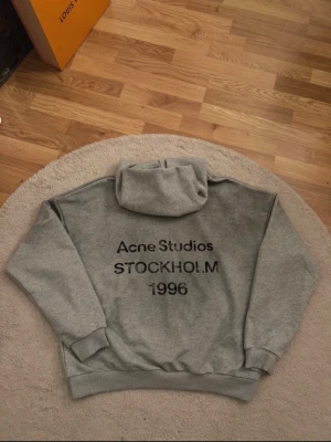 Acne Studios Stockholm 1996 Hoodie – grå - Mycket eftertraktad Acne Studios Stockholm 1996-hoodie i en ren grå färg. Minimalistisk skandinavisk design med en avslappnad och exklusiv känsla.  • Storlek S (oversized passform) • Ny utan taggar • 100 % äkta (etiketter visas) • Finns även i svart, kolla min profil  Perfekt för en stilren vardagslook eller uppklädd streetwear-styling. Först till kvarn. 