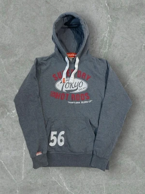 Superdry Hoodie Tokyo Hot Rods Grey/Red/White – Size L - Superdry hoodie featuring “Tokyo Hot Rods” print in grey with red and white details. Soft, warm and comfortable with a classic fit. Perfect for everyday wear and street style. Size Large. Great condition.