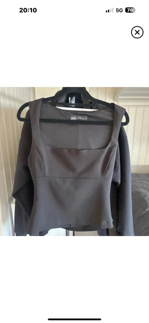 Svart linnetopp från Zara, S - Svart linnetopp från Zara i storlek S. Toppen har breda axelband och en fyrkantig urringning som ger en stilren och modern look. Materialet är slätt och har en lätt stretch för skön passform. Perfekt att styla med jeans eller kjol för en trendig vibe.