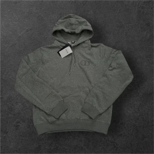 Grå D*or Hoodie Storlek Medium - Säljer en helt ny d*or hoodie i storlek medium. Hoodien är i nytt skick med taggarna kvar. En stilren och exklusiv produkt från d*or med den klassiska CD loggan på bröstet. Denna hoodie passar perfekt till vardags och till en avslappnad look. Hoodien är gjord av 100% bomull och är mycket välgjord 