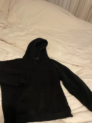 Svart hoodie från BikBok  - Svart hoodie från BikBok i storlek S. Klassisk modell med huva, metallöljetter och stor magficka framtill. Mjuk bomullskänsla och ribbade muddar vid ärmslut och nederkant. Perfekt för chill dagar eller när du vill ha en enkel och clean look.
