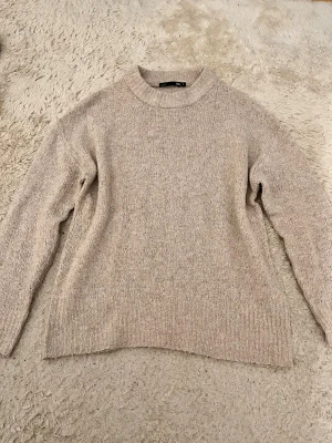 Beige stickad tröja från lager 157 - Säljer en beige stickad tröja från lager 157 med hög hals och långärmad design. Tröjan har en mjuk och grovstickad struktur som ger en chill och avslappnad vibe. Perfekt för att hålla sig varm under kyliga dagar.