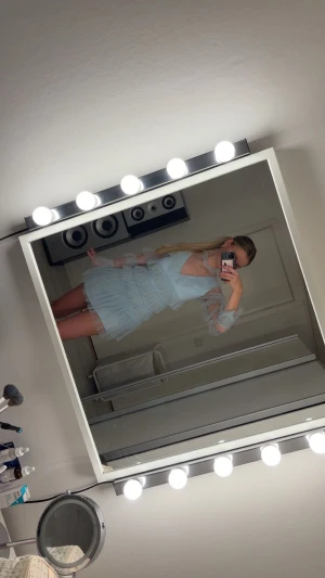 Ljusblå volangklänning med spets/mesh - Supersöt ljusblå kortklänning med flera lager volanger och transparenta meshdetaljer på ärmarna. Klänningen har v-ringad hals och långärmade ärmar med volanger längs hela armen. Är extremt lik den blåa volang klänningen ifrån By Malina