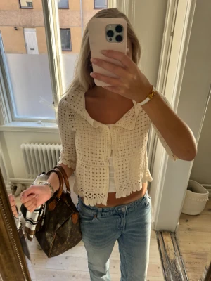 Vit virkad bolerotopp med volangkant - Säljer en söt vit bolerotopp med virkat rutmönster och volangkant vid ärmslut och nederkant. Toppen har trekvartsärm och en bred krage som ger en chill och trendig vibe. Perfekt att styla över ett linne eller crop top för en fräsch look.