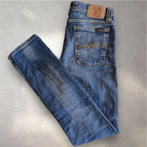 Blå jeans från Nudie Jeans - Säljer ett par klassiska blå jeans från Nudie Jeans med fem fickor och snygga slitningar.  Storlek W28 L32. Skriv vid frågor!