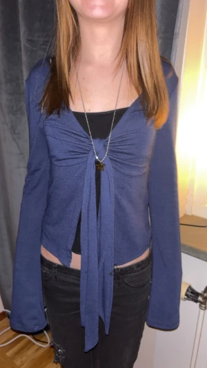 Mörkblå långärmad tröja - Säljer en mörkblå bolerotopp med omlott-design och långa ärmar. Toppen har snygg knytning framtill som ger en cool och trendig look. Materialet är mjukt och stretchigt, perfekt för att styla med jeans eller kjol. Croppad passform som visar lite midja.