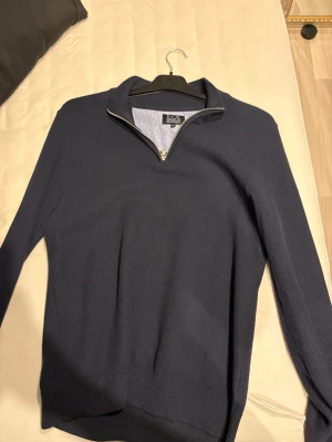 Marinblå half zip tröja från S.C.W - Snygg marinblå långärmad tröja från S.C.W med half zip-dragkedja vid kragen. Tröjan har ribbade muddar och är tillverkad i mjuk bomull, perfekt för dig som gillar stilren och enkel design.