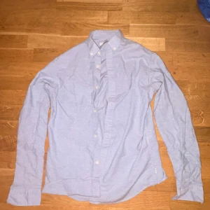 Ljusblå skjorta från Jack & Jones - Ljusblå skjorta från Jack & Jones med klassisk krage och knappar framtill. Skjortan har lång ärm och är tillverkad i mjuk bomull. Enkel och stilren design som funkar till många olika looks. Perfekt för dig som gillar en clean och chill stil.