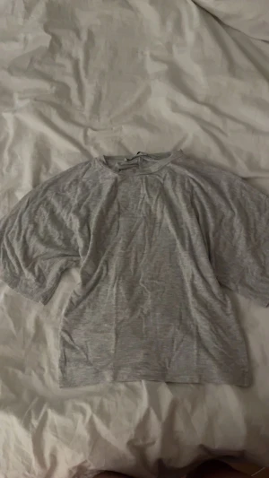 Grå T-shirt med tight midja  - Säljer en enkel grå topp från lager 157 i storlek XS. Modellen är loose på toppen och tightare i midjan. Materialet känns mjukt och lätt mot huden .