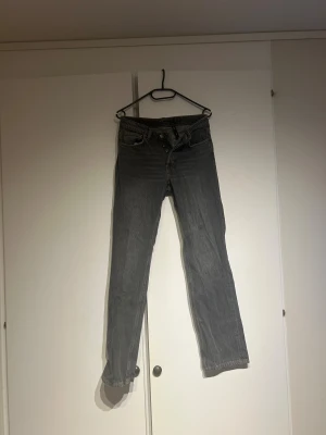 Grå weekday  jeans straight fit - Säljer ett par grå weekday jeans med klassisk straight fit och fem fickor. Jeansen har en knappgylf och är tillverkade i slitstarkt denim. Perfekt för dig som gillar en tidlös look med raka ben och normal passform.