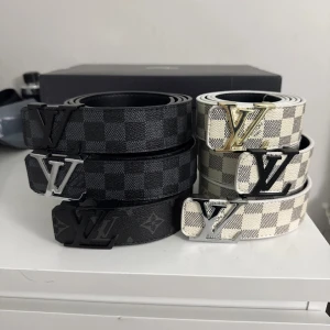 Louis Vuitton rutiga bälten - Säljer flera Louis Vuitton bälten med klassiskt rutigt mönster i svart och grått samt vitt och beige. Bältena har stora LV-spännen i svart, silver och guld. Perfekt accessoar för att lyfta din outfit med lyxig känsla och ikonisk design.