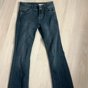Blå bootcut jeans med raka ben - Snygga mörkblå jeans från Mango med klassisk bootcut. Jeansen dragkedja med två knappar framtill. Passsar både 36 och 38