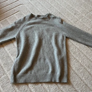 Grå stickad tröja med rund hals - Mysig grå stickad tröja med rund halsringning och ribbade muddar vid ärmslut och nederkant. Perfekt för lager-på-lager och chill dagar. Enkel och stilren design som funkar till det mesta.