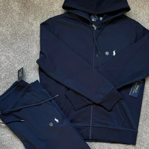 Marinblå hoodie från Polo Ralph Lauren - Snygg marinblå hoodie från Polo Ralph Lauren med huva och dragkedja framtill. Tröjan har långa ärmar, ribbade muddar och klassisk Polo-logga broderad på bröstet. Perfekt för chill dagar eller när du vill vara extra bekväm. ALLT JAG SÄGER ÄR 12/10 ❄️