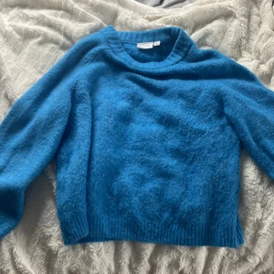 Blå stickad tröja från VILA - Mysig blå stickad tröja från VILA i storlek XS. Tröjan har en klassisk rund halsringning, ribbade muddar och är långärmad. Perfekt för lager-på-lager och chill dagar. Färgen är klarblå och materialet känns fluffigt och mjukt.