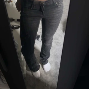 Svarta straight jeans från Levi's - Säljer ett par svarta jeans från Levi's med klassisk femficksdesign och raka ben. Jeansen har normal passform och midja, med snygga slitningar och tydliga sömmar. Perfekt för dig som gillar en enkel och tidlös look.