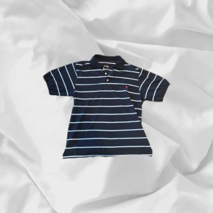 Polo Ralph Lauren piké - Clean Ralph piké i storlek L, sitter perfekt på 182-190 beroende på vikt! – enkel att matcha och skön att bära. Ett stilrent val, noggrant utvalt med omsorg av AM Clothing.  📩 Frågor? Hör gärna av dig! 📲 Följ oss här på Plick för fler uppdateringar. ♻️ Tack för att du handlar mer hållbart med AM Clothing!