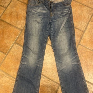 Nudie Jeans low slim Jim - Säljer ett par klassiska blå jeans från nudie . Jeansen har snygga slitningar, tyvärr har storleks lappen suddats ut så finns ej bild, strl är 32/30