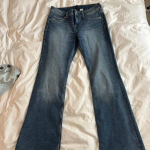 Blå bootcut jeans med utsvängda ben - Snygga blå jeans med bootcut-modell och utsvängda ben. Klassisk femficksdesign och låg midja. Jeansen har en lätt tvättad look och är tillverkade i mjukt denimtyg som ger en skön passform. Dessa är väldigt bekväma, har de i fler färger, men köpte fel storlek! Aldrig använda❣️