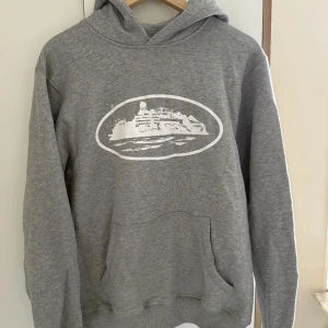 Grå hoodie med tryck från Corteiz - Grå hoodie från Corteiz.Klassisk känguruficka framtill och huva. Mjuk och skön, perfekt för chill dagar. 