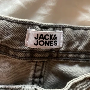 Grå jeans från Jack & Jones, stl 158 - Säljer ett par grå jeans från Jack & Jones i storlek 158. Klassisk femficksmodell med raka ben och snygga sömmar. Jeansen har en neutral grå färg som passar till det mesta och är tillverkade i ett slitstarkt bomullstyg.Pris kan diskuteras 