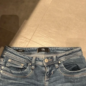 Blå bootcut jeans från LTB, W25 L30 - Säljer ett par blå jeans från LTB, modell Valerie. Jeansen har bootcut passform och låg midja, klassisk femficksdesign och snygg tvätt. Perfekta för dig som gillar en tidlös look med lite utsvängda ben. Materialet är jeans i bomullsmix. Skick 9/10