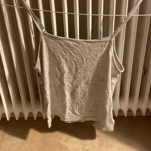 Ljusgrå linnetopp från lager 157 - Säljer en enkel och stilren ljusgrå linnetopp från lager 157. Toppen har smala justerbara axelband och är tillverkad i mjuk bomull. Perfekt för varma dagar och enkel att matcha med jeans eller shorts. Sitter som en xxs 