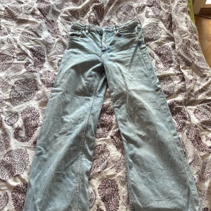 Ljusblå wide jeans med raka ben - Säljer ett par ljusblå jeans med klassisk femficksdesign och raka, breda ben. Jeansen har normal midja och är tillverkade i mjukt denimtyg. Passar dig som gillar en avslappnad och trendig look med lite extra utrymme i benen.