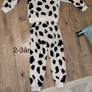 Svartvita mjukisbyxor med dalmatinermönster - Ett sött set med tröja och byxor i ett dalmatinermönster. Storleken är uppskattad till 2-3 år.Supermjuka och fluffiga mjukisbyxor i vitt med svarta dalmatinerfläckar. Byxorna har resår i midjan och muddar vid bensluten för extra komfort. Perfekta för chill dagar hemma eller som mysplagg. Super varma och sköna kläder perfekt för vintertid ❄️ 