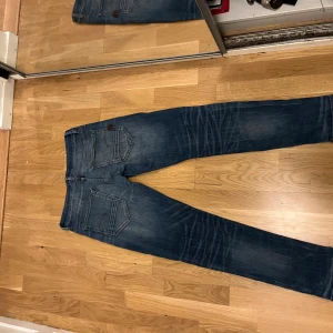 Blå jeans G-Star  - Snygga blå jeans från G-Star, med en lite lösare slim fit. Jeansen har klassisk femficksdesign, subtila slitningar och en mörk tvätt med ljusare partier. Passar dig som gillar en modern och smal siluett. Materialet är stretchigt jeans för extra komfort.