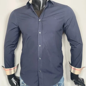 Burberry Skjorta - Stilren mörkblå skjorta från Burberry med klassiska rutiga detaljer på insidan av krage och armar. Cond: 8/10. Retail:  4,800 SEK.