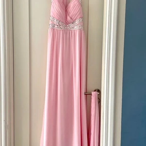Balklänning  - En rosa balklänning i fint skick med strass stenar. Samt en sjal som man kan ha över axlarna. Storlek XS/S. Säljs för 980kr, kan hämtas och skickas (frakt ingår inte)😊