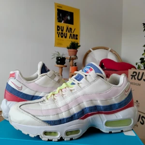 Nike Air Max 95 panache courdroy - Nike Air Max 95 i vitt läder med detaljer i blå manchester/courdroy, samt läderdetaljer i ljusrosa, neongult och rött. Använda ett par gånger men i fint skick. Stl 40 dam.  Kan skicka fler bilder vid förfrågan.