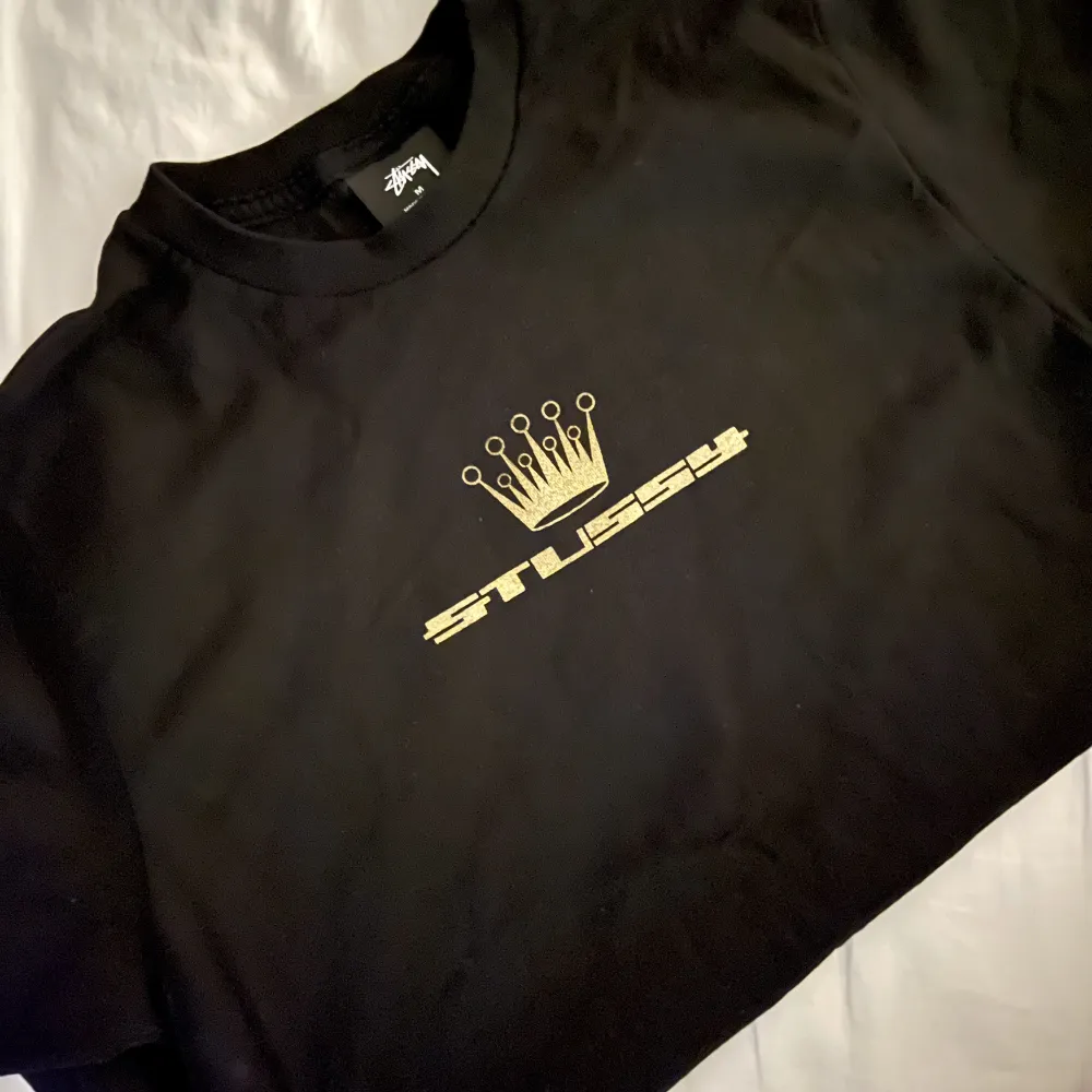 T-shirt från Stüssy med guldig logo och en krona på. Använt en-två gånger. . T-shirts.