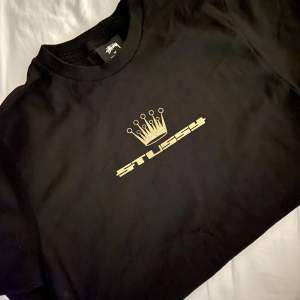T-shirt från Stüssy med guldig logo och en krona på. Använt en-två gånger. 