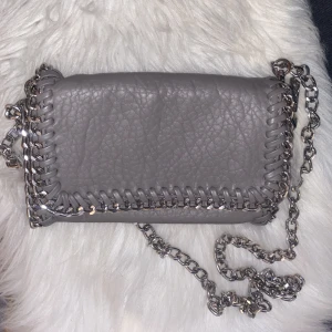 Tiamo väska - Grå Tiamo väska i den minsta modellen. Väskan har två innerfack, ett med dragkedja och ett utan. Då många var intresserade kör vi budgivning som startar 11/1 kl. 8. Fraktkostnaden är inte inkluderad i priset💕