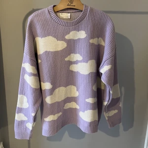 Stickad tröja - En ljuslila stickad tröja med vita moln från Asos (herr). Storlek XL. Köpt på Plick men aldrig använd på grund av för stor. I begagnat skick.