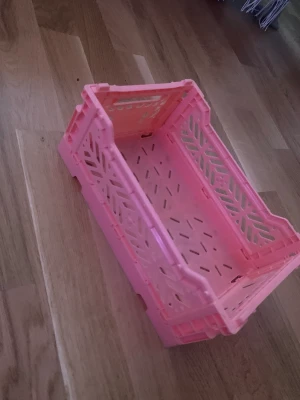 En plast låda som man kan fälla ihop. - Den är typ lite skrik rosa. Fin att ha lite små saker i eller typ smink.