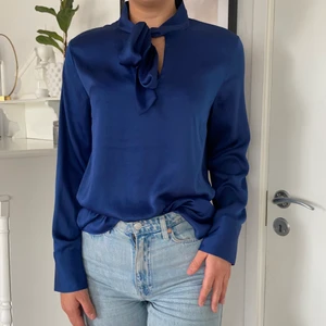Mrökblå blus knytblus - En knytblus i silkesmaterial. Gulddetaljer på ärmar. Holly white x Lindex. Storlek M och jag är 178cm lång 