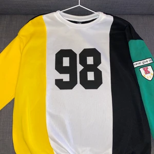 Sweatshirt, s -  En svart kört i storlek S. Den är randig och har en gul och en grön arm och baksidan är helt svart. 