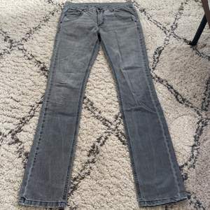 Gråa low waist jeans, straight slim fit. Innerbenslängd: 80cm, höftmått: 38,5cm rakt över. Bra skick med cool detalj på ena bakfickan