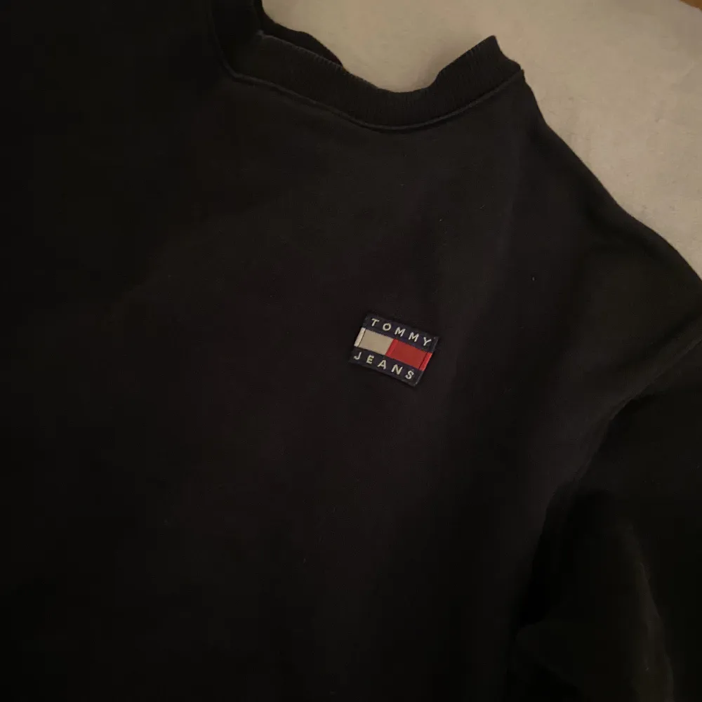 Snygg, lite croppas och svart sweatshirt från Tommy jeans, köpt från Nelly.com. Tyvärr för liten för mig. Det är storlek S och den är true to size. Bra skick, inga fläckar eller andra slitningar då den inte är använd så mycket.😊 Frakt ingår ej. . Tröjor & Koftor.