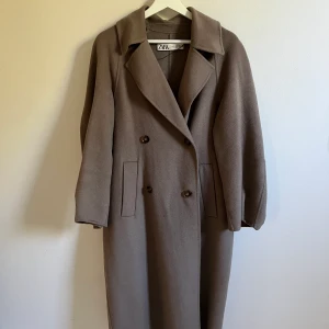 Kappa - En lila grå kappa med balong armar som e lite kortare. 