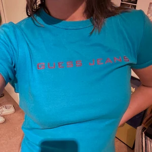 Guess Jeans baby tee - Blå guess jeans t-shirt. Står storlek M men tycker den är mer en S. Köpt i Madrid second hand och knappt använd av mig💖