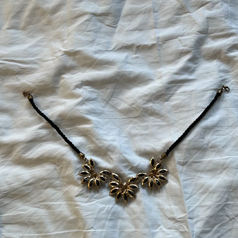 Ett svart halsband med blommor. . Accessoarer.