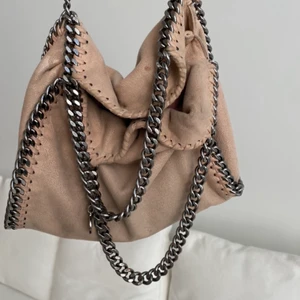 Stella McCartney väska - INTRESSEKOLL! Säljer min ljusrosa/beiga Stella McCartney Falabella foldover bag då den tyvärr inte kommer till så mycket användning längre💕 Dustbag medföljer! Skriv för fler bilder på skick m.m! Nypris; ca 8000:- (svarar långsamt på denna annons)