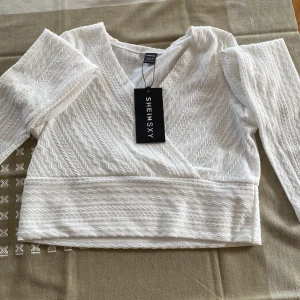 Topp  - En vit topp köpt från SHEIN. Har endast prövat toppen på mig en endaste gång. Prislappen kvar. Storlek L. Tror även att den passar dom som har M i kläder😊