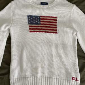 ”The iconic flag sweater” I väldigt fint skick. En liten fläck (se bild 2) på en ärmen. Storlek XL i barn storlek. Passar som en S/Liten Medium