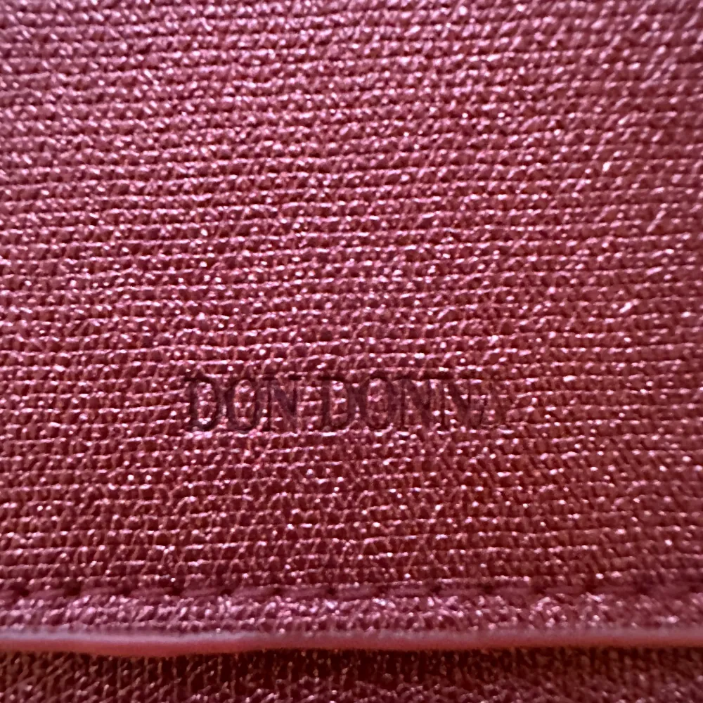 Aldrig använd Don Donna väska. Den är röd glittrig. Jätte praktiskt då man kan reglera hur lång bandet kan vara. Den har även tre rymliga fack inuti. En av facken har blixtlås.. Väskor.